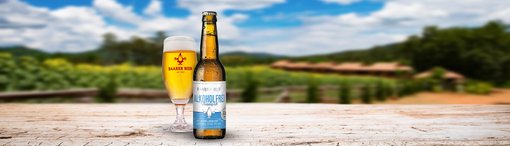 Baarer Bier Alkoholfrei Feinherb Flasche mit einem Glas Bier und einer Landschaft im Hintergrund